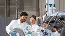A man and a woman are analyzing a metal foil in a laboratory.