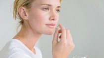 Woman taking an Omega-3 capsule --- Image by © Eric Audras/Onoky/Corbis