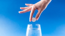 Headache medicine. Woman hand puts aspirin into glass with water. Health care concept with blue background.; Shutterstock ID 1329336281; purchase_order: BASF_PHA-002786; job: Bildkauf Website; client: BASF SE / Pharma Solutions; other: Katharina Weber