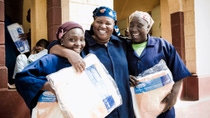 Three happy women wearing blue robes hold basf packages  Three happy women wearing blue robes hold basf packages