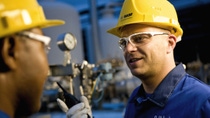 Two employees in discussion wearing yellow hard hat and safety goggles Two employees in discussion wearing yellow hard hat and safety goggles
