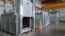 Interior of an industrial thermal furnace with refractory-lined walls and metal rail tracks.