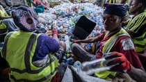 Drei Menschen sitzen in einem Haufen leere Plastikflaschen und sortieren sie aus. Drei Menschen sitzen in einem Haufen leere Plastikflaschen und sortieren sie aus.