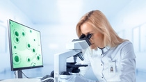 Female Research Scientist Looks at Biological Samples Under Microscope. She and Her Colleagues Work in a Big Modern Laboratory/ Medical Centre. Female Research Scientist Looks at Biological Samples Under Microscope. She and Her Colleagues Work in a Big Modern Laboratory/ Medical Centre.