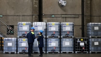 A man and a woman in work clothes operate a factory machine.