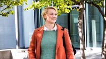 A woman in an orange coat smiling.  A woman in an orange coat smiling.