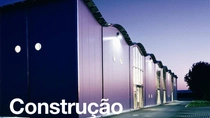 Um exterior moderno do edifício ao anoitecer com luzes acesas.&nbsp; O texto na imagem diz: “Construção”