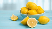 Plate with lemons on blue wooden table over abstract background Plate with lemons on blue wooden table over abstract background