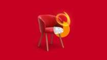 A red armchair with wooden legs in front of a red background. An orange light swirl appears on the chair.