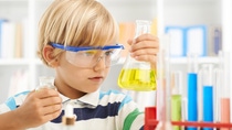 Young chemist looking at the flask with bright yellow liquid