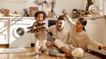 happy multi ethnic family: little boy laughing and playing with   toy airplane in front of his  his parents in the kitchen at home happy multi ethnic family: little boy laughing and playing with   toy airplane in front of his  his parents in the kitchen at home