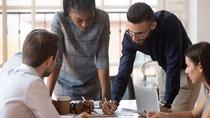 Focused multiracial corporate business team people brainstorm on marketing plan financial report gather at office table meeting.
