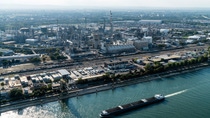 Ein Bild, das den BASF-Hauptsitz in Ludwigshafen und seine zahlreichen Produktionsanlagen zeigt. Der Steamcracker, das Herz des Verbunds, in seiner Mitte. Im Vordergrund sehen wir den Rhein und ein Containerschiff.