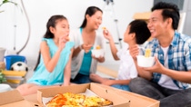 Box of pizza on the background of family eating at home