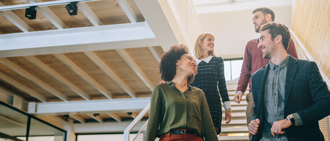 Four employees chatting while walking down the stairs
