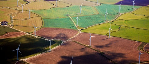 Wind Turbines amidst some colorful fields in Kent viewed from air.