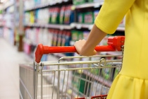 Eine Frau fährt mit einem Einkaufswagen durch den Supermarkt 