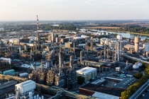 Aerial view of the BASF Verbund site in Ludwigshafen, showing an extensive industrial complex with production facilities, pipelines, and towers along a river landscape.
