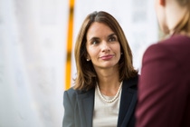 Two female scientists in white lab coats with the BASF logo and protective goggles stand in the laboratory and look into the camera.