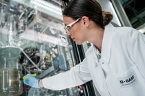 A woman shining a light on a cylinder filled with liquid.