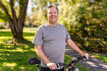 A man in a grey shirt hoding a bike. A man in a grey shirt hoding a bike.
