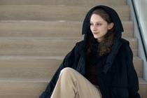 Frau mit schwarzer Jacke aus loopamid, sitzend auf einer Treppe