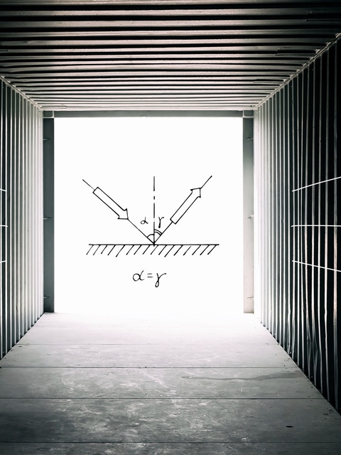 Interno di un container di spedizione vuoto e scuro, rivolto verso le porte aperte del container: le equazioni scientifiche e gli schizzi sono sovrapposti su un quadrato di luce che passa attraverso le porte aperte