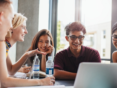 University students sitting together at table with books and laptop. Happy young people doing group study in library.; Shutterstock ID 508251865