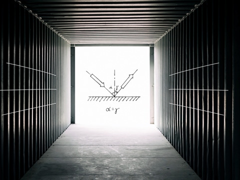 Inside a dark, empty shipping container looking towards the open container doors - scientific equations and sketches are overlaid on a bright square of light coming through the open doors. Inside a dark, empty shipping container looking towards the open container doors - scientific equations and sketches are overlaid on a bright square of light coming through the open doors.