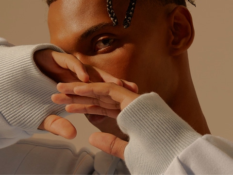 A man posing with his hands slightly in front of his face.