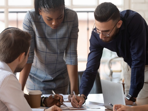 Focused multiracial corporate business team people brainstorm on marketing plan financial report gather at office table meeting.