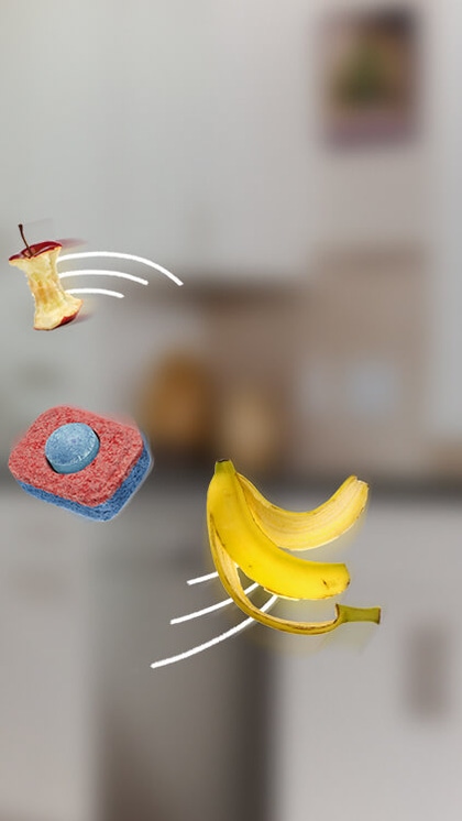 Una banana, un torsolo di mela e una foglia che ruotano attorno ad una pastiglia per lavastoviglie