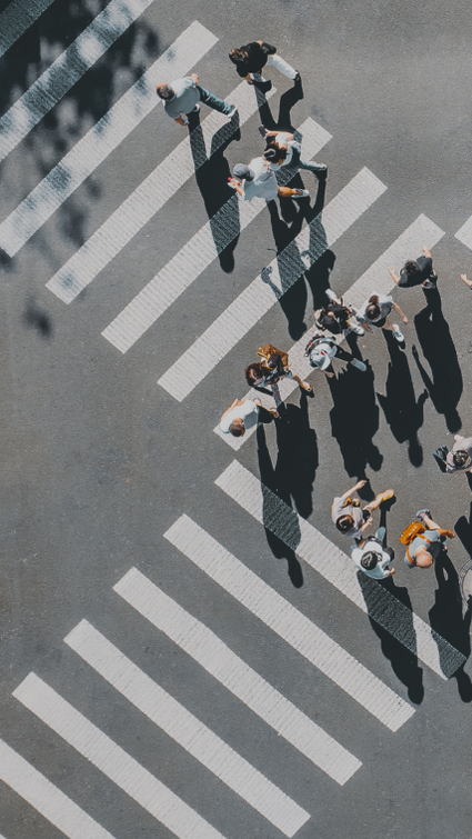 Birds-eye-view of people walking across a large crosswalk at an intersection. Birds-eye-view of people walking across a large crosswalk at an intersection.