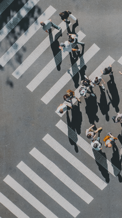Birds-eye-view of people walking across a large crosswalk at an intersection.