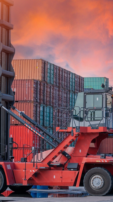Crane lifting up container and unloading cargo into the import-export zone in yard.