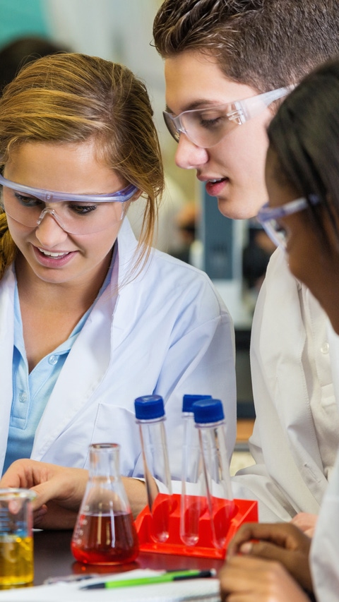 Teens using chemistry set during high school science experiement