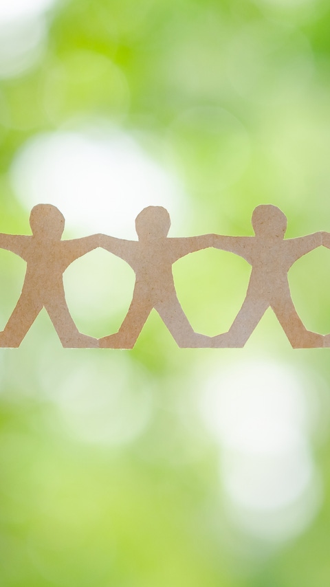 Closeup hand hold the paper human chain on green background in the forest, CSR and sustainable development concept