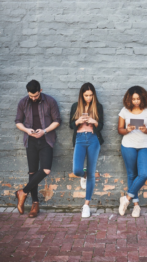 Shot of a group of young people using their wireless devices together outdoors Shot of a group of young people using their wireless devices together outdoors