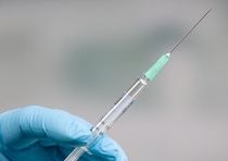 Close up of doctor's hand in medical gloves holding a syringe in front of a clinic room Close up of doctor's hand in medical gloves holding a syringe in front of a clinic room