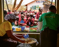 Zwei Frauen von der Essensausgabe reichen den Schülern ihr Mittag. Zwei Frauen von der Essensausgabe reichen den Schülern ihr Mittag.