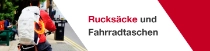 Eine Person von hinten auf einem Fahrrad trägt einen weißen Rucksack mit VAUDE- und BASF-Logo sowie einem orangefarbenen Lichtring. Der Text lautet: „Transformed Backpacks."