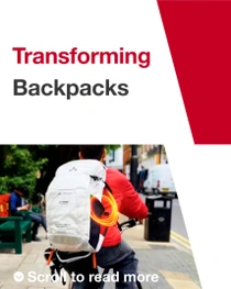 A person seen from behind on a bicycle wears a white backpack with VAUDE and BASF logo and an orange light ring. The text reads: "Transformed Backpacks." A person seen from behind on a bicycle wears a white backpack with VAUDE and BASF logo and an orange light ring. The text reads: "Transformed Backpacks."