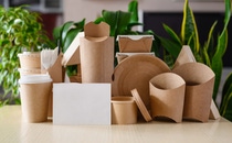 A set of paper packaging and disposable tableware and a white blank sheet for advertising. The concept of advertising eco-friendly packaging. A set of paper packaging and disposable tableware and a white blank sheet for advertising. The concept of advertising eco-friendly packaging.