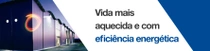 Um exterior moderno do edifício ao anoitecer com luzes acesas.  Um redemoinho de luz paira sobre a borda do edifício. O texto diz: “Vida mais aquecida e com eficiência energética”.