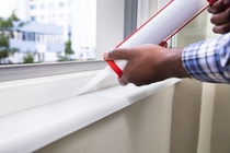 Close-up Of Person Hand Applying Silicone Sealant With Silicone Gun On Window Close-up Of Person Hand Applying Silicone Sealant With Silicone Gun On Window