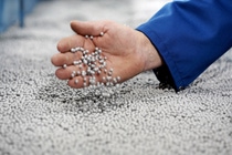 Aufgeschäumtes Neopor® ist federleicht: Mit einem Griff in die silbergrauen Kugeln kontrolliert ein Mitarbeiter das Ergebnis des Vorschäumens.