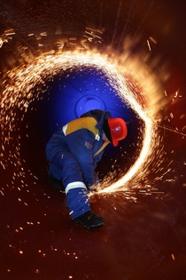 Ein Mann in Arbeitskleidung schweißt in der Gaspipeline.