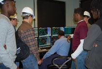 BASF Operator Technician Willie Roberts shows Blake Nappier and Devontae Young of Millry High School, Hunter Harrell and Clayton Elmore of Leroy High School, and Corey Donaldson and Deanthony Holcombe of Washington County High School basic computer assimilations of the chemical process and how it relates to the physical structure of the equipment in a control room in the Light Stabilizers Unit.