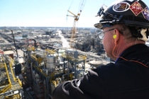 Man in hard hat looking out at a manufacturing plant