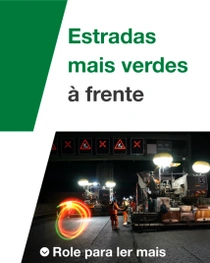 Uma construção de estrada à noite com trabalhadores e máquinas. Um redemoinho de luz paira sobre a cena. O texto diz: “Estradas mais verdes à frente”.